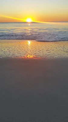sunset over ocean waves washing onto beach