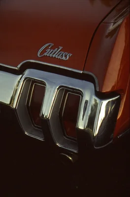 chrome cutlass emblem on burgundy classic car