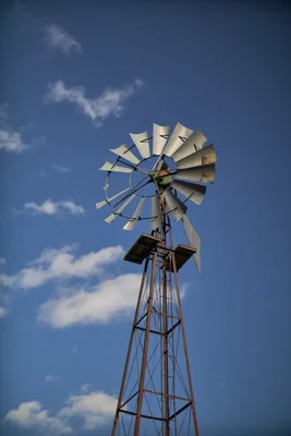 rustic windmill against blue sky with clouds