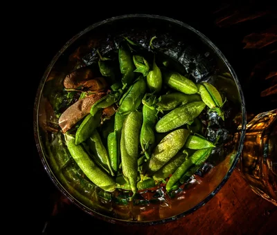 snap peas in glass bowl with water