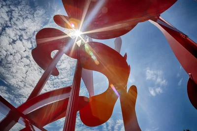 red metal sculpture against sunny blue sky