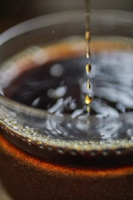 golden liquid dripping into dark coffee cup