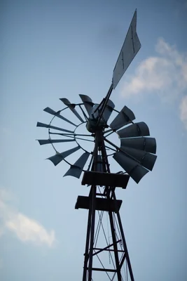 windmill silhouette against blue sky with clouds