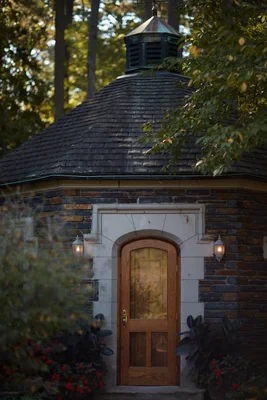 stone cottage with arched doorway in wooded setting